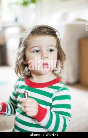 Babymädchen spielen mit Lippenstift Stockfoto