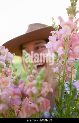 Porträt der jungen Frau mit Haufen von Löwenmäulchen (Antirrhinum) vom Bauernhof Blumenfeld hautnah Stockfoto