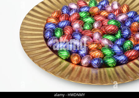 Goldene Platte voller Schokolade Ostereier auf weiß. Stockfoto