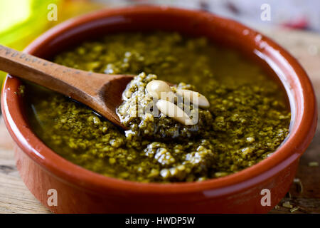 Nahaufnahme von einem Steingut-Schale mit Italienische Pesto-Sauce garniert mit einigen Pinienkernen auf einem rustikalen Holztisch Stockfoto