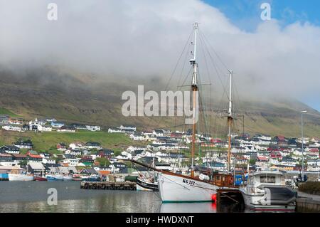 Dänemark, Färöer Inseln, Insel Bordoy, Klaksvik, Schoner aus Holz in den Hafen, Stadt und Berge, Wolken im Hintergrund Stockfoto