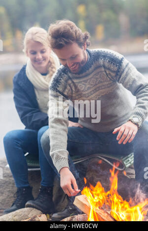 Brautpaar sitzend Lagerfeuer am Seeufer Stockfoto
