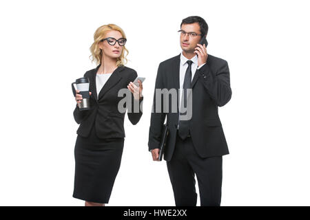 Schöne Geschäftsfrau in Gläsern mit Kaffee und gut aussehend Geschäftsmann hält Ledermappe und telefonieren mit Handy. Paar stehen isoliert o Stockfoto