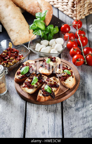 Vorspeise-Bruschetta mit getrockneten Tomaten, Oliven und Mozarella. Italienische Küche. Ansicht von oben Stockfoto