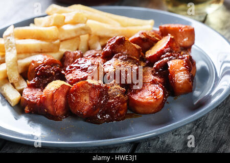 Traditionelle deutsche Currywurst - Stücke Wurst mit Curry-Sauce und Pommes frites Stockfoto