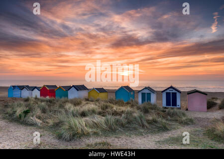 Auf einer ruhigen Dawn Mitte März geht die Sonne auf den Dünen an der Suffolk-Meer-Stadt Southwold über die berühmte Linie der Strandhütten. Stockfoto