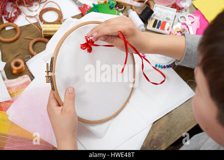 Junge auf Reifen, Hand Closeup und rotes Band auf weißen Textilien bestickt erfährt, Nähen, job, Ausbildung, Handarbeit und Kunsthandwerk-Konzept Stockfoto