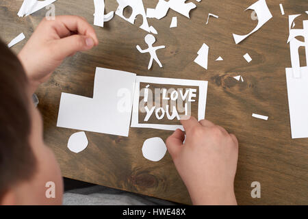 junge macht Origami - Auto und Familie, Kinder, Eltern, ich liebe dich Text, Draufsicht auf Holz Hintergrund Stockfoto