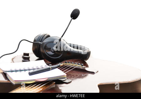 Notizblock Stift Kopfhörer und akustischer Gitarre in weißem Hintergrund Stockfoto