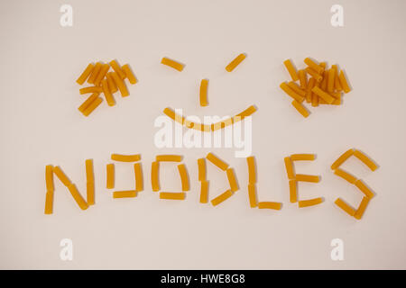 Smiley-Gesicht und Nudeln-Text aus Pennette Pasta auf weißem Hintergrund gemacht Stockfoto