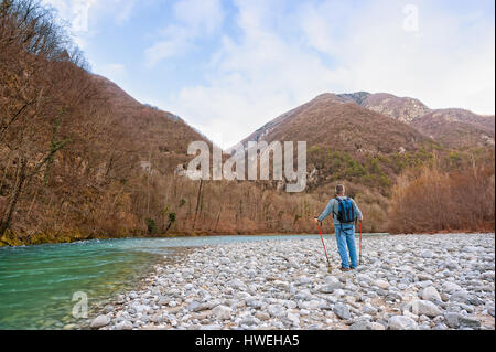 Wanderer am Ufer eines Flusses. Wandern in Richtung Berg. Rambler etwa 60 Jahre alt. Stockfoto