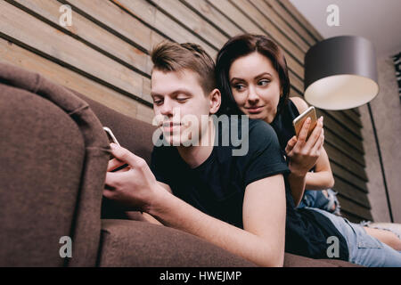 junge hübsche Mädchen liegend auf den Kerl und sieht in seinem Handy. Mann das Telefon verwenden und in sozialen Netzwerken kommuniziert. Stockfoto