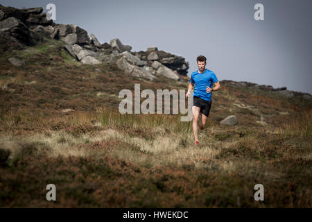 Männliche Läufer liefen aus Stanage Edge, Peak District, Derbyshire, UK Stockfoto