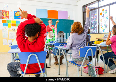 Rückansicht des primären Schülerinnen und Jungen mit Handzeichen im Klassenzimmer Stockfoto