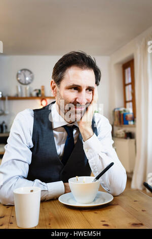Lächelnd reifen Mann mit Kinn einerseits beim Frühstück in der Küche Stockfoto