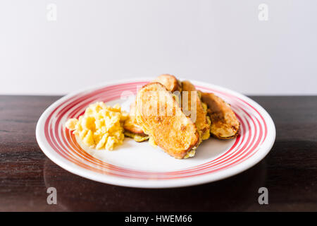 French Toast mit Rührei auf einer runden Platte. Tisch aus Holz Stockfoto