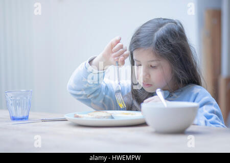 Mädchen essen pochiertes Ei-Frühstück am Küchentisch Stockfoto