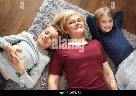 Großmutter und Enkel entspannend auf Teppich Stockfoto