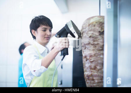 Junge Frau schneiden Kebab-Fleisch in Fast-Food-shop Stockfoto