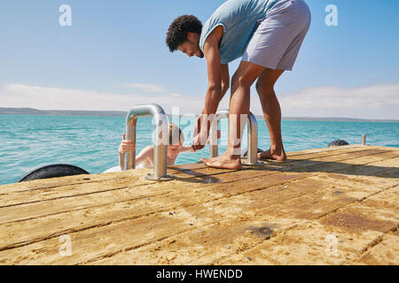 Vater Sohn auf Hausboot Sonnendeck klettern zu helfen Stockfoto