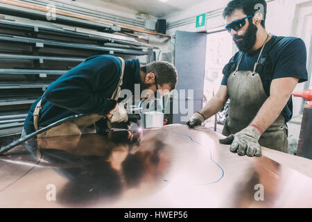 Zwei Schlosser Schneiden Blech Kupfer an Schmiede Werkbank Stockfoto