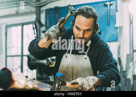 Männliche Schlosser Hämmern Metall Schmiede Workshop Stockfoto