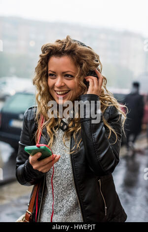 Frau in Straße anhören von Musik über Kopfhörer Stockfoto