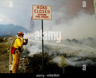 FBS04 20031025 RANCHO CUCAMONGA, CA, Vereinigte Staaten: Ein Feuerwehrmann einen Wasserschlauch verwenden, um ein Lauffeuer in Rancho Cucamonga, Kalifornien-Bereich auf Samstag, 25. Oktober 2003 zu begießen. Waldbrände in der Region haben Tausende von Hektar Wald und erzwungene Evacutation der Häuser in dieser Gegend verbrannt... Foto von Francis Specker Stockfoto