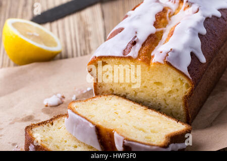 Hausgemachte glasierten Zitronen Sandkuchen auf rustikalen Holztisch, in Scheiben geschnitten und fertig zum Verzehr Stockfoto