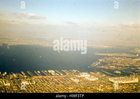 Blick nach Westen vom Sunset Park und Red Hook, Brooklyn, über Upper New York Bay, New Jersey Ufer des Hudson River, 1957. Herzstück im Hafen ist die Freiheitsstatue und Ellis Island. Am rechten Rand ist Gouverneur der Insel, gleich hinter der Spitze des südlichen Manhattan am Battery Park. Im Hintergrund sind der Hafen von Bayonne und Jersey City, New Jersey sichtbar im Westen. Im Vordergrund rechts sind die Arme des Erie Basin am Gowanus Bay Terminal in Red Hook, Brooklyn. Die Bush Terminal Company Piers Linie die Uferpromenade im Zentrum Vordergrund. Gowanus Express Stockfoto