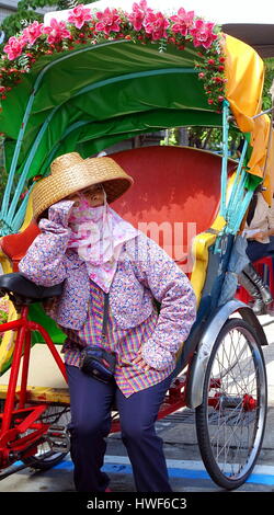 KAOHSIUNG, TAIWAN--25. Juli 2015: ein weiblicher Zyklus-Rikscha-Fahrer tragen eine traditionelle Hakka Stil Strohhut, wartet auf neue Kunden. Stockfoto