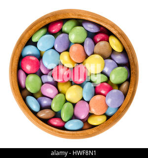 Bunte Pralinen in Holzschale. Zucker-beschichtete Schokoladenwaren in acht verschiedenen Farben. Oblate Spheroid Bonbons geformt. Stockfoto