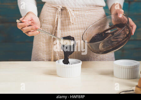 Haus Frau trägt Schürze machen. Schritte der Herstellung Kochen Schokolade Kuchen. Teig mischen Zutaten vorbereiten Stockfoto