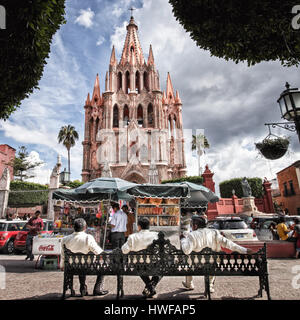 Drei Spieler der Mariachi entspannen Sie auf einer Bank in der Nähe der Basilika in San Miguel de Allende, Mexiko. Stockfoto