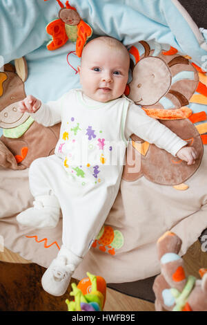 Kleine niedliches neugeborenes Baby liegt auf dem Rücken auf einer weichen Decke mit Tröster Spielzeug Stockfoto