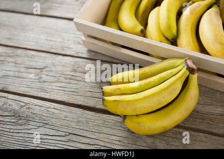 Bananen in Holzkiste auf Holztisch Stockfoto