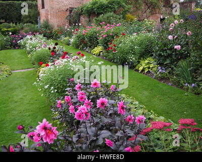 Chenies Manor versunkene Garten im späten September. Rasen und Pflanzen Grenzen, dunkel rosa Dahlien und vielfältige krautige Pflanzen und Laub sind immer noch lebendig. Stockfoto