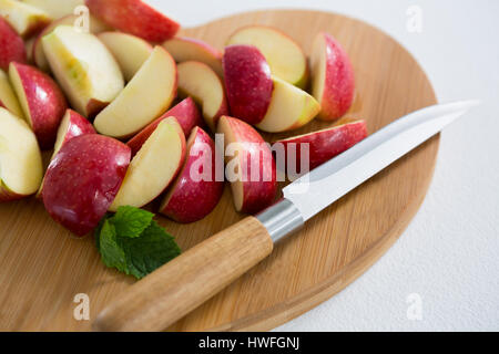 Scheiben von rotem Apfel und Messer auf Schneidebrett auf weißem Hintergrund Stockfoto
