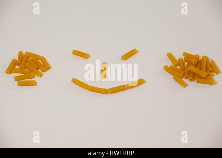 Smiley-Gesicht gemacht aus Pennette Pasta auf weißem Hintergrund Stockfoto