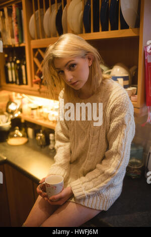 Porträt der Frau hält eine Kaffeetasse in der Küche zu Hause Stockfoto