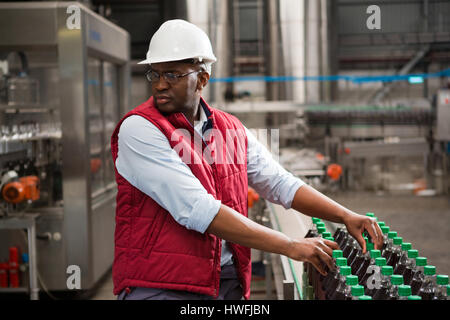 Schweren männlichen Arbeitnehmer, Vermittlung von Saft-Flaschen in Fabrik Stockfoto