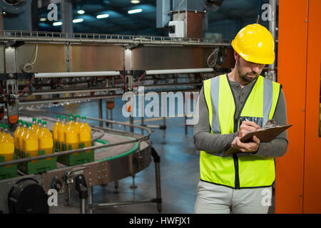 Schweren männlichen Arbeitnehmer schriftlich auf Zwischenablage werkseitig Saft Stockfoto