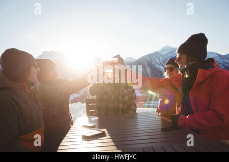 Skifahrer-Freunden Toasten Glas Bier im Skigebiet auf hellem Sonnenlicht Stockfoto