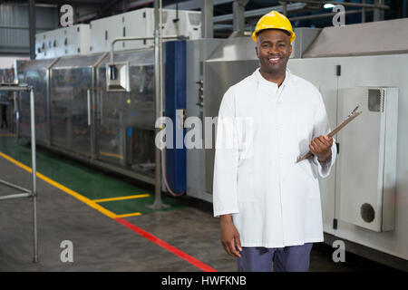 Porträt des Lächelns männlichen Arbeitnehmer halten Zwischenablage im Lager Stockfoto