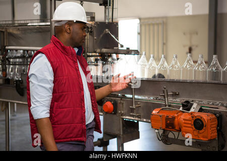Zuversichtlich männliche Bediener Überwachung Flaschen auf Produktionslinie in Fruchtsaft Fabrik Stockfoto