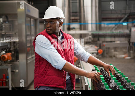 Schweren männlichen Arbeitnehmer, Vermittlung von Saft-Flaschen in Fabrik Stockfoto