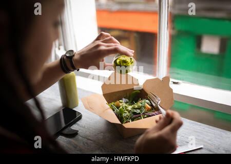 Frau, Gießen grünen Soße auf einen Salat in CafÃƒÂ © Stockfoto