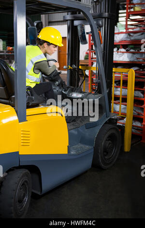 Zuversichtlich Arbeitnehmerin fahren Gabelstapler in Fabrik Stockfoto
