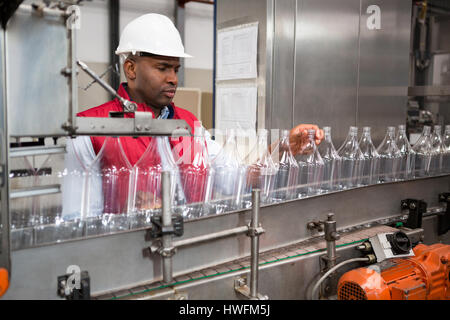 Zuversichtlich männliche Mitarbeiter untersuchen Flaschen Saft Fabrik Stockfoto