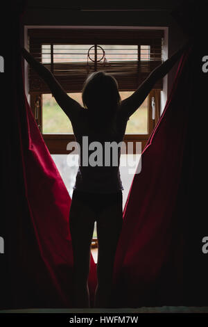 Frau öffnen Vorhänge Schlafzimmer zu Hause Stockfoto